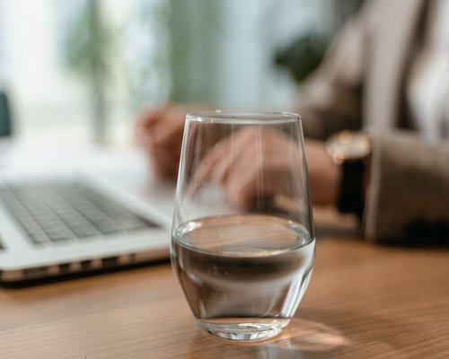 A glass of water sitting on a modern office desk